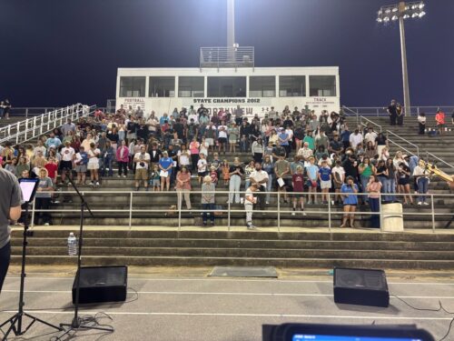 students standing on bleachers during Faith of Fields event in Escambia County